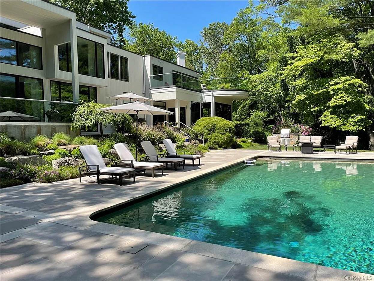 A pool with chairs and a building in the background
