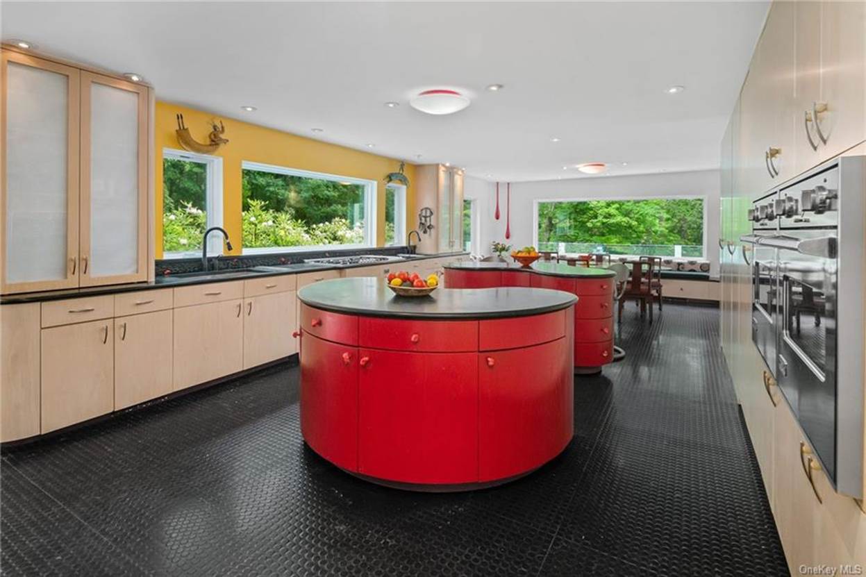 A kitchen with red cabinets and black floor
