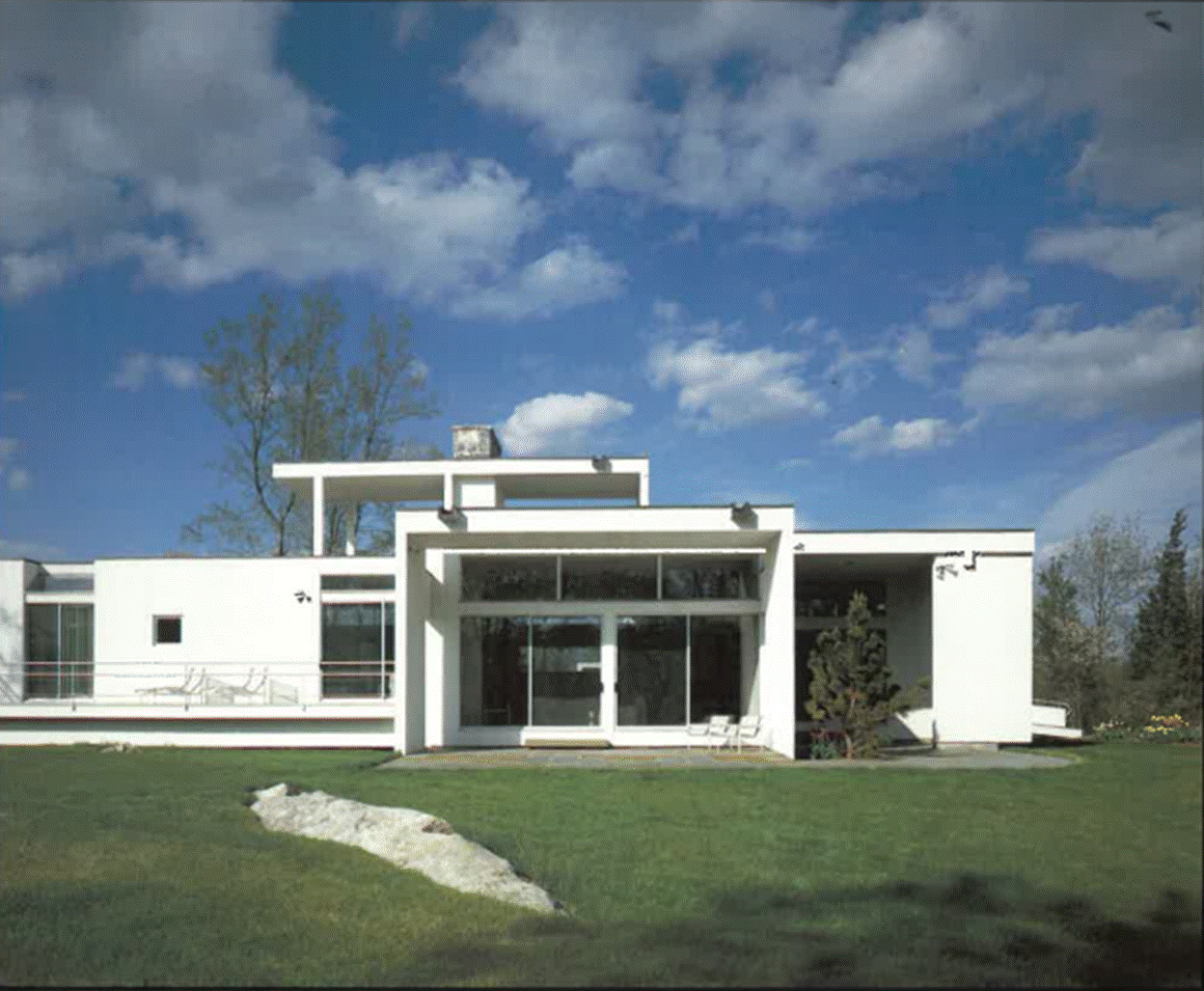 A white house with a lawn and blue sky
