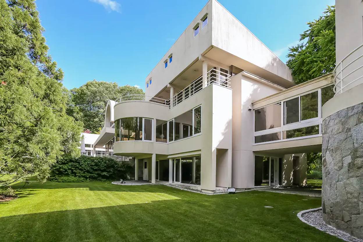 A large white house with a lawn and trees
