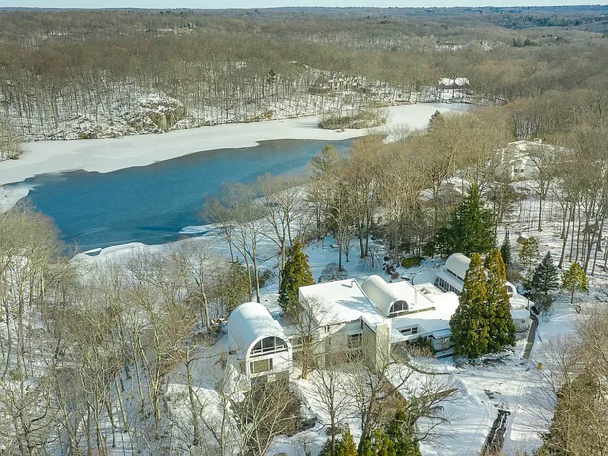 A house surrounded by snow and a river
